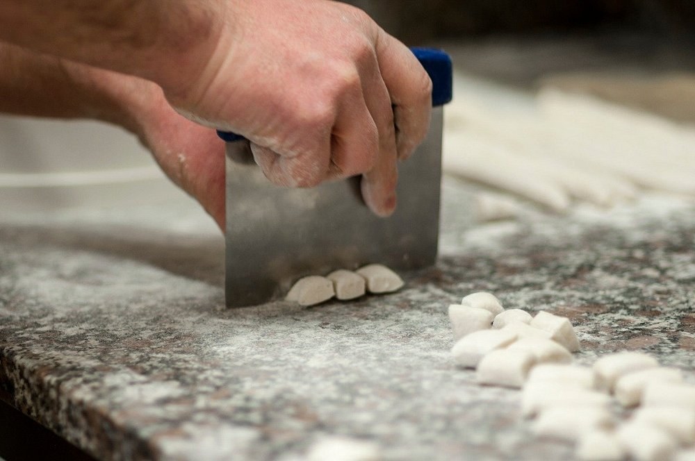 Preparazione a mano degli gnocchi sul banco infarinato